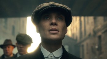 Movie still from “Peaky Blinders” (2013), created by Steven Knight – A man wearing a hat and a suit looking to his left; Close Up shot, Low angle