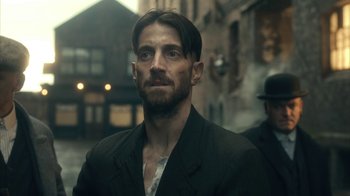 Movie still from “Peaky Blinders” (2013), created by Steven Knight – A person wearing a suit; Close Up shot, Over the shoulder angle