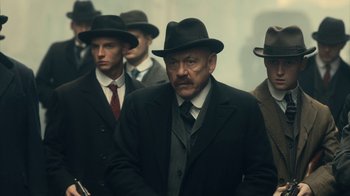 Movie still from “Peaky Blinders” (2013), created by Steven Knight – A group of men wearing hats and suits; Medium shot, Low angle