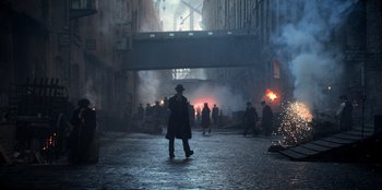 Movie still from “Peaky Blinders” (2013), created by Steven Knight – A group of people walking down a street; Wide shot, High angle