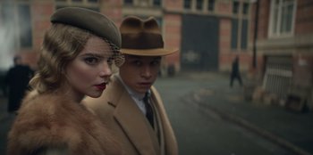 Movie still from “Peaky Blinders” (2013), created by Steven Knight – A man and a woman standing next to each other on the street; Close Up shot, Low angle