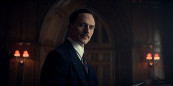 Movie still from “Peaky Blinders” (2013), created by Steven Knight – A man wearing a suit and tie in a dark room; Close Up shot, Low angle