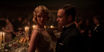 Movie still from “Peaky Blinders” (2013), created by Steven Knight – A man and a woman standing next to each other in front of candles; Medium shot, Low angle