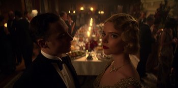 Movie still from “Peaky Blinders” (2013), created by Steven Knight – A man and a woman standing next to each other in front of a table; Close Up shot, Low angle