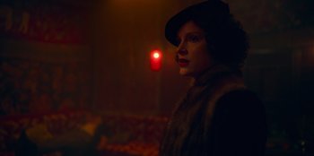 Movie still from “Peaky Blinders” (2013), created by Steven Knight – A woman wearing a hat standing next to a street light; Close Up shot, Low angle