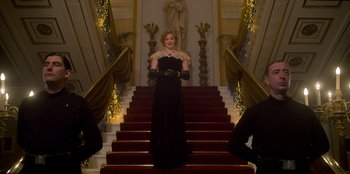 Movie still from “Peaky Blinders” (2013), created by Steven Knight – A woman in a black dress standing on top of a set of stairs; Wide shot, Low angle
