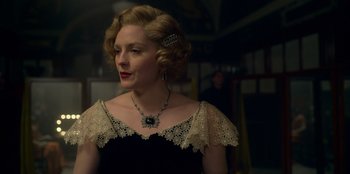 Movie still from “Peaky Blinders” (2013), created by Steven Knight – A woman in a black dress with a necklace and earrings; Close Up shot, Low angle