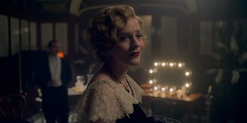 Movie still from “Peaky Blinders” (2013), created by Steven Knight – A woman with blonde curly hair wearing a black dress; Close Up shot, Over the shoulder angle