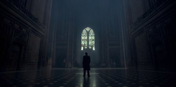 Movie still from “Peaky Blinders” (2013), created by Steven Knight – A man standing in front of a stained - glass window; Extreme Wide shot, Low angle