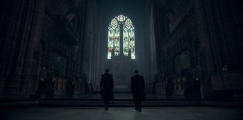 Movie still from “Peaky Blinders” (2013), created by Steven Knight – Two men are standing in front of a stained - glass window; Extreme Wide shot, Low angle