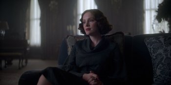 Movie still from “Peaky Blinders” (2013), created by Steven Knight – A woman sitting in a chair in front of a window; Medium shot, Low angle
