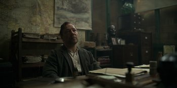 Movie still from “Peaky Blinders” (2013), created by Steven Knight – A man sitting at a table in front of a map; Medium shot, Over the shoulder angle