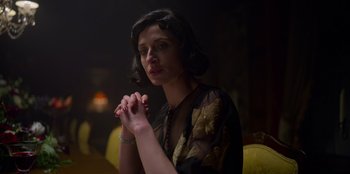 Movie still from “Peaky Blinders” (2013), created by Steven Knight – A woman is praying in a dimly - lit room; Close Up shot, Low angle