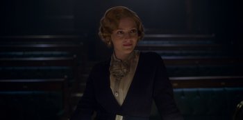 Movie still from “Peaky Blinders” (2013), created by Steven Knight – A woman in a black jacket is standing in a dark room; Medium shot, Low angle