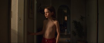 Movie still from “Penguin Bloom” (2020), directed by Glendyn Ivin – A young boy standing in a room with his arms outstreched; Medium shot, Over the shoulder angle