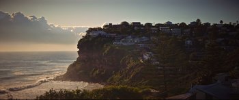 Movie still from “Penguin Bloom” (2020), directed by Glendyn Ivin – A view of houses on the side of a cliff; Extreme Wide shot, Low angle