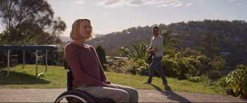 Movie still from “Penguin Bloom” (2020), directed by Glendyn Ivin – A man and a woman sitting on a bench in the grass; Wide shot, Over the shoulder angle