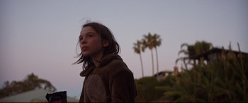 Movie still from “Penguin Bloom” (2020), directed by Glendyn Ivin – A young girl standing in front of palm trees at dusk; Close Up shot, Low angle