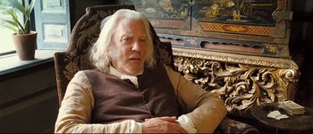 Movie still from “Pride & Prejudice” (2005), directed by Joe Wright – An older man sitting in a chair in front of a painting; Medium shot, High angle