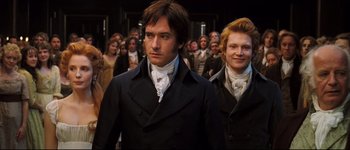 Movie still from “Pride & Prejudice” (2005), directed by Joe Wright – A man and a woman are walking in front of a group of people; Medium shot, Low angle