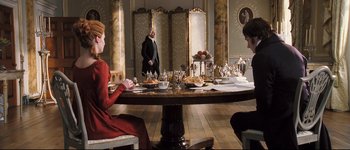 Movie still from “Pride & Prejudice” (2005), directed by Joe Wright – A group of people sitting around a table with plates of food on top of it; Wide shot, Over the shoulder angle
