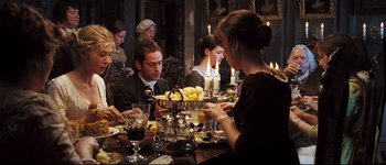 Movie still from “Pride & Prejudice” (2005), directed by Joe Wright – A group of people sitting around a table with plates of food on it; Medium shot, High angle