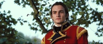 Movie still from “Pride & Prejudice” (2005), directed by Joe Wright – A man in a red and gold uniform stands in front of a tree; Close Up shot, Low angle