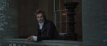 Movie still from “Pride & Prejudice” (2005), directed by Joe Wright – A man leaning on a wall in front of a fountain; Medium shot, Low angle