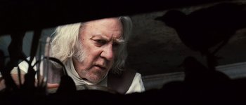 Movie still from “Pride & Prejudice” (2005), directed by Joe Wright – An older man with long white hair looking at the camera; Close Up shot, Over the shoulder angle