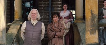 Movie still from “Pride & Prejudice” (2005), directed by Joe Wright – A group of people standing next to each other in front of a brick wall; Medium shot, Low angle