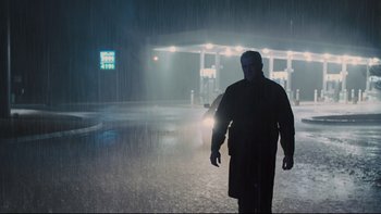 Movie still from “Prisoners” (2013), directed by Denis Villeneuve – A man walking in the rain at a gas station at night; Wide shot, Low angle