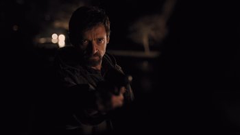 Movie still from “Prisoners” (2013), directed by Denis Villeneuve – A man holding a gun while standing in the dark; Close Up shot, Over the shoulder angle