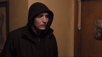 Movie still from “Prisoners” (2013), directed by Denis Villeneuve – A man wearing a black hooded jacket in a room; Close Up shot, High angle
