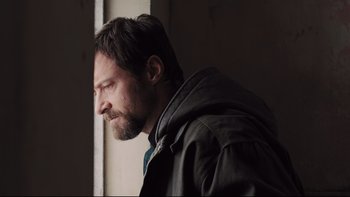 Movie still from “Prisoners” (2013), directed by Denis Villeneuve – A man with a goatee looking out of a window; Close Up shot, Low angle