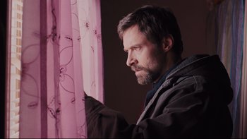Movie still from “Prisoners” (2013), directed by Denis Villeneuve – A man looking out of a window at a pink curtain; Close Up shot, Low angle