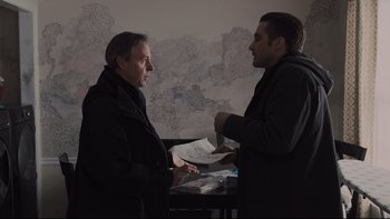 Movie still from “Prisoners” (2013), directed by Denis Villeneuve – Two men are standing in front of a table; Medium shot, Over the shoulder angle