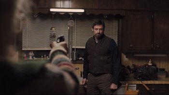 Movie still from “Prisoners” (2013), directed by Denis Villeneuve – A man standing in a kitchen next to an animal; Medium shot, Over the shoulder angle