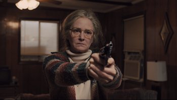 Movie still from “Prisoners” (2013), directed by Denis Villeneuve – An older woman holding a gun in a room; Medium shot, Low angle