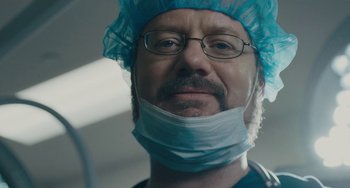 Movie still from “Private Life” (2018), directed by Tamara Jenkins – A man wearing a surgical cap and glasses; Close Up shot, Low angle