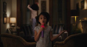 Movie still from “Private Life” (2018), directed by Tamara Jenkins – A little girl holding a microphone up to her mouth; Medium shot, Over the shoulder angle