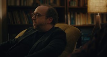 Movie still from “Private Life” (2018), directed by Tamara Jenkins – A man sitting in a chair in front of a book shelf; Close Up shot, Over the shoulder angle