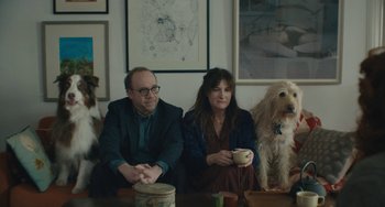 Movie still from “Private Life” (2018), directed by Tamara Jenkins – A man and a woman sitting at a table with two dogs; Wide shot, High angle
