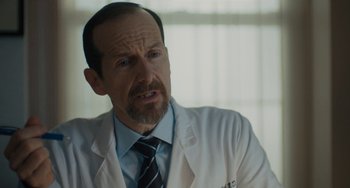 Movie still from “Private Life” (2018), directed by Tamara Jenkins – A man in a white lab coat and a tie; Close Up shot, Over the shoulder angle