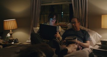 Movie still from “Private Life” (2018), directed by Tamara Jenkins – A man and a woman sitting on a bed with a laptop; Medium shot, High angle