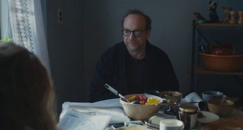 Movie still from “Private Life” (2018), directed by Tamara Jenkins – A man sitting at a table with a bowl of fruit; Medium shot, Over the shoulder angle