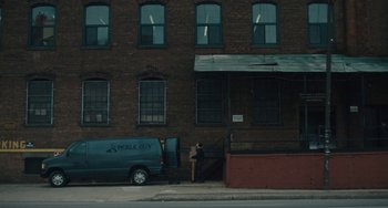 Movie still from “Private Life” (2018), directed by Tamara Jenkins – A van parked in front of a brick building on the side of the street; Extreme Wide shot, High angle