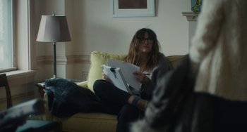 Movie still from “Private Life” (2018), directed by Tamara Jenkins – A woman sitting on a couch holding papers; Medium shot, Over the shoulder angle