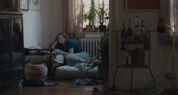 Movie still from “Private Life” (2018), directed by Tamara Jenkins – A woman sitting on top of a couch in a living room; Wide shot, High angle