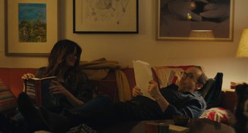 Movie still from “Private Life” (2018), directed by Tamara Jenkins – A man and a woman sitting on a couch reading; Medium shot, Over the shoulder angle