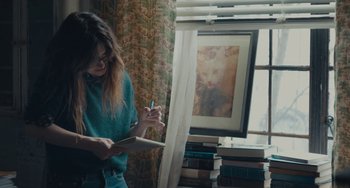 Movie still from “Private Life” (2018), directed by Tamara Jenkins – A woman writing on a book in front of a window; Medium shot, High angle